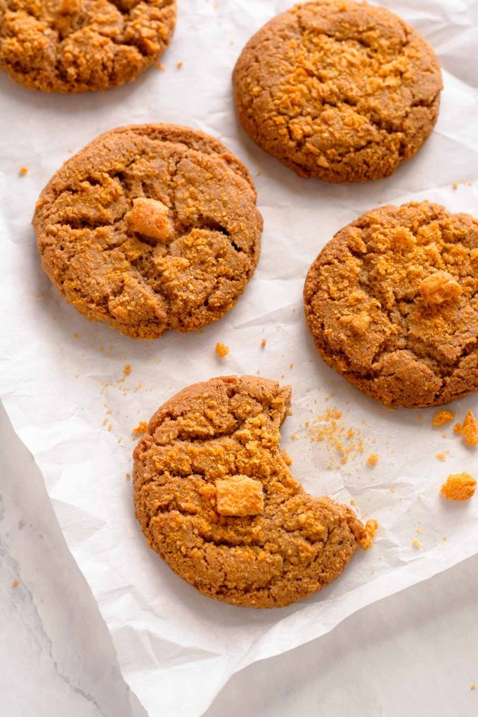 overhead shot of three Cap'n Crunch Cookies on parchment, one with a bite taken out of it.