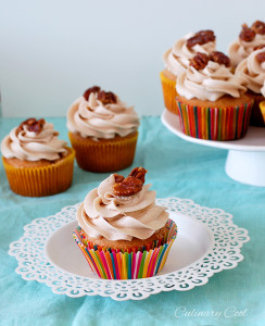 cupcake on a small white plate, with several other cupcakes in background on cake stand