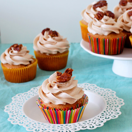 cupcake on a small white plate, with several other cupcakes in background on cake stand
