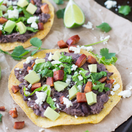 Crispy tortilla topped with refried beans, chorizo and cheese