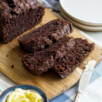 Chocolate loaf with three slices cut from it. The three slices are on a cutting board, slightly overlapping each other.