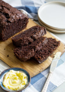 Chocolate loaf with three slices cut from it. The three slices are on a cutting board, slightly overlapping each other.