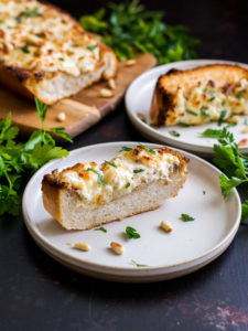 A small plate with a slice of garlic toast topped with cream cheese and parsley