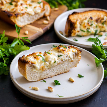 A small plate with a slice of garlic toast topped with cream cheese and parsley