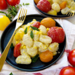 Sweet Corn and Roasted Tomato Gnocchi on a black plate with gold fork