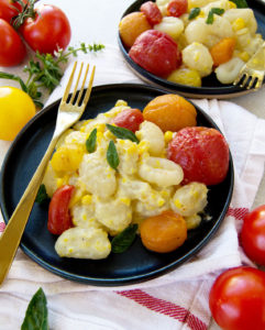 Sweet Corn and Roasted Tomato Gnocchi on a black plate with gold fork