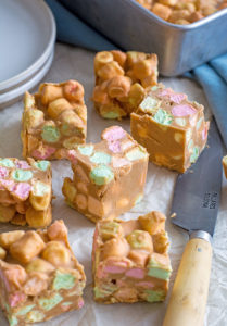 Close up of seven marshmallow squares. three are tilted to the side, to expose the colourful marshmallows inside.