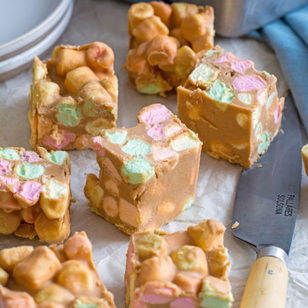 Close up of seven marshmallow squares. three are tilted to the side, to expose the colourful marshmallows inside.