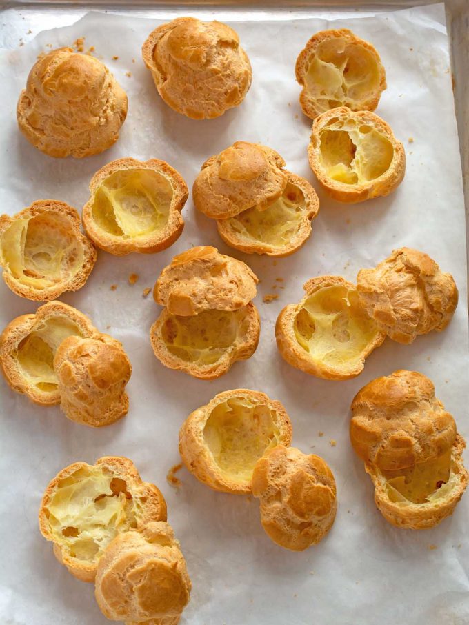 Pâte à choux puffs, cut in half spread out on a baking tray
