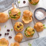 Pâte à choux puffs, cut in half, four have a curried turkey filling inside them, several others are just cut in half, and empty