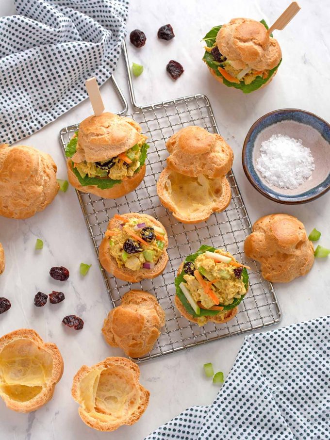 Pâte à choux puffs, cut in half, four have a curried turkey filling inside them, several others are just cut in half, and empty