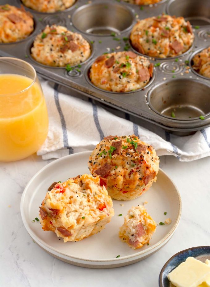 two muffins sitting on a plate, and one has a bite out of it