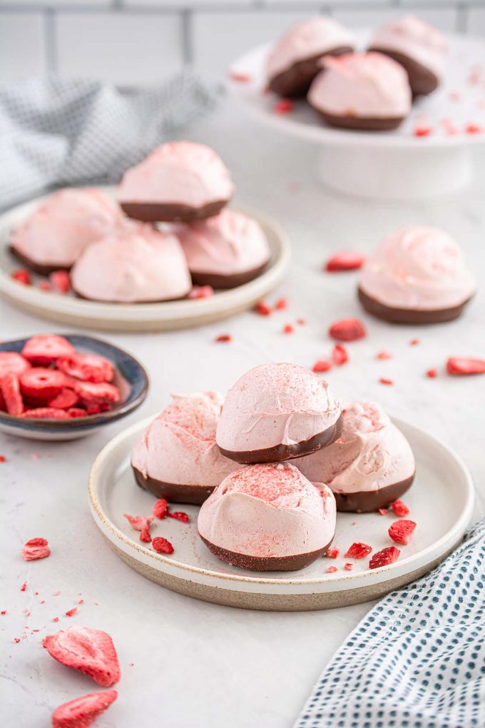 pink meringues dipped in chocolate and piled on a small plate.