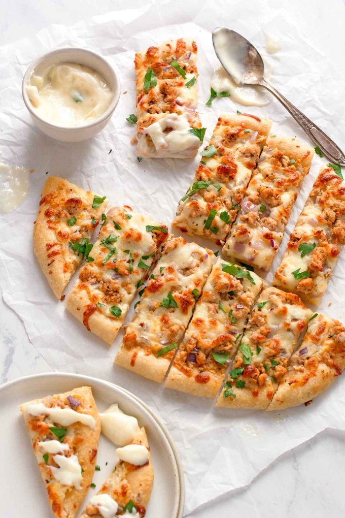 rectangular pieces of pizza, separated slightly, with some pieces dipped in a creamy sauce