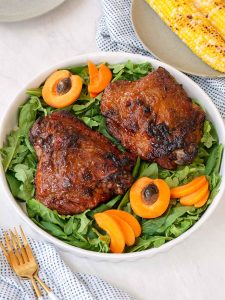 Two turkey thighs on a bed of greens, with apricot halves