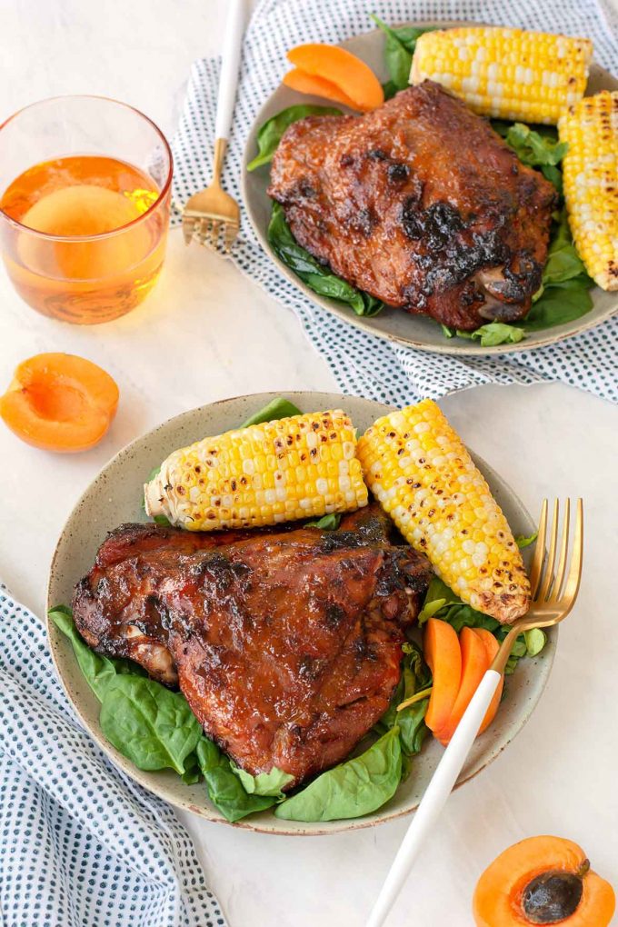 turkey thigh on a plate with corn, green salad and apricot slices