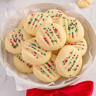 Round plate full of shortbread cookies. The cookies are topped with red, white and green sprinkles.