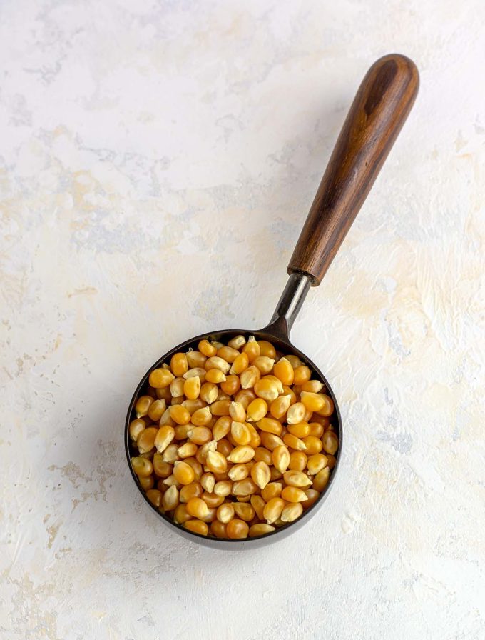 kernels of un-popped pop corn in a black onyx measuring cup