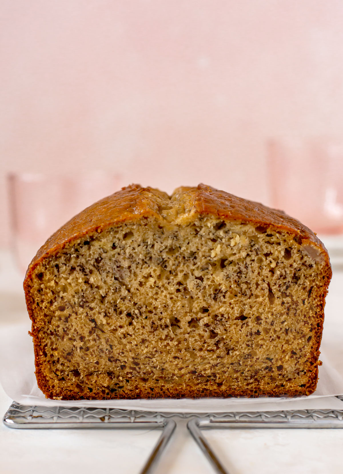 Close up shot of a loaf of banana bread with a slice cut off the front to expose the crumb on the inside.