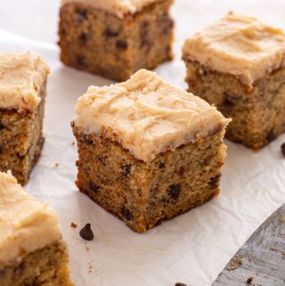 Close up of a square of cake with frosting, showing the mini chocolate chips inside the cake.